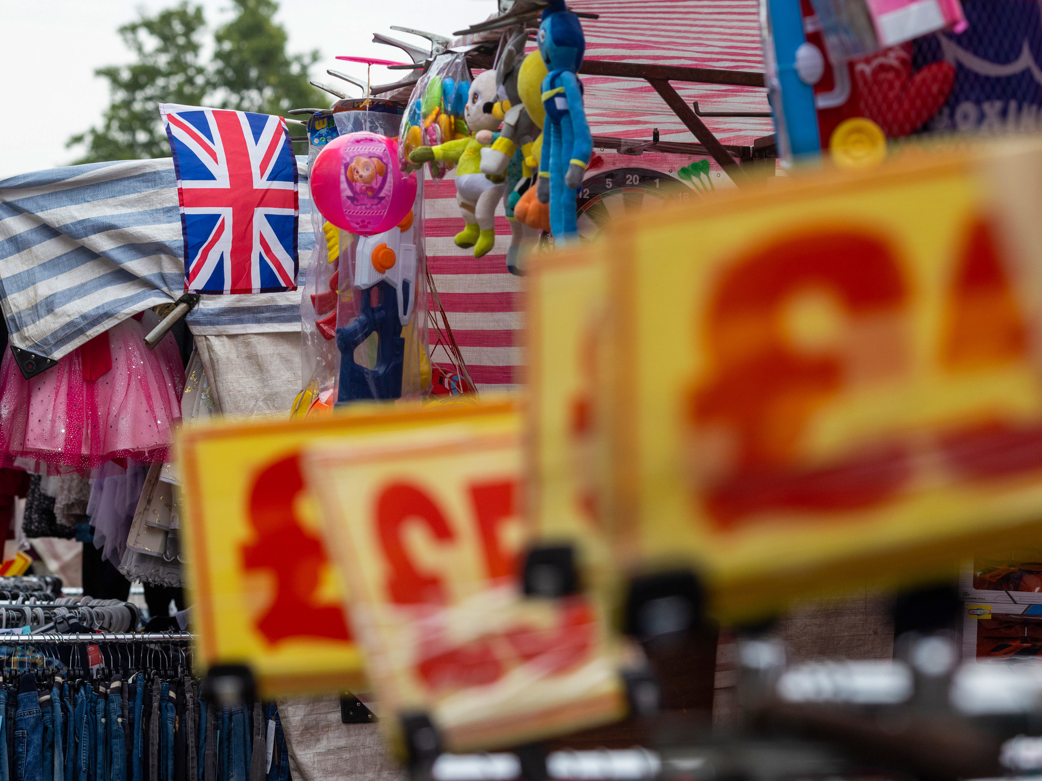caption: A British Union Jack flies above a clothing market stall in Barking, U.K., last week.