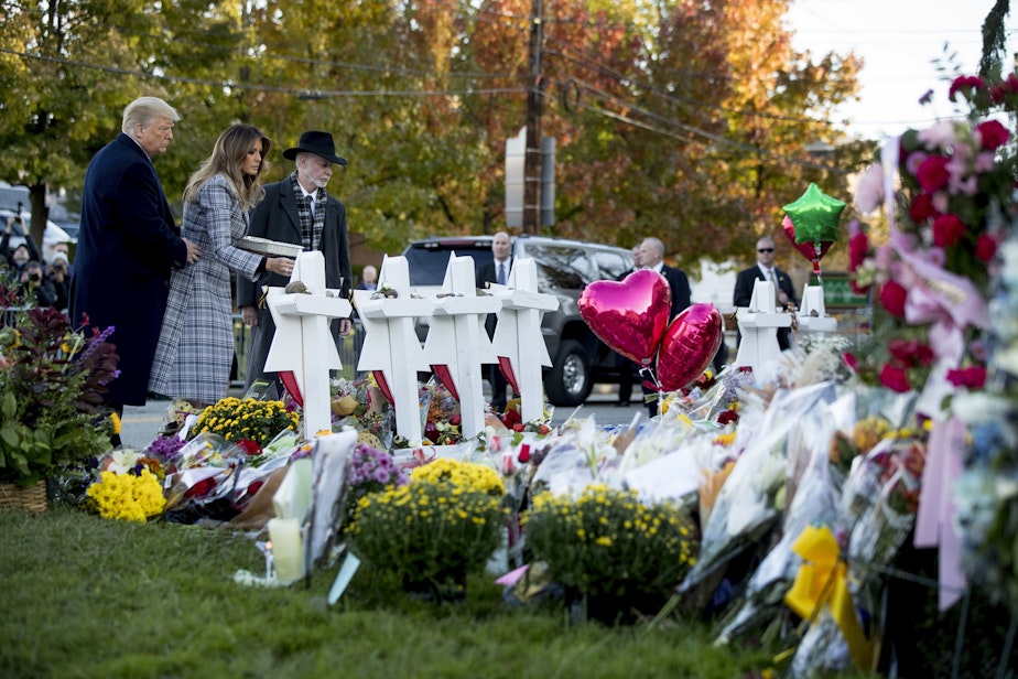 caption: First lady Melania Trump, accompanied by President Donald Trump, and Tree of Life Rabbi Jeffrey Myers, right, places a white flower at a memorial for those killed at the Tree of Life Synagogue in Pittsburgh, Tuesday, Oct. 30, 2018. (AP Photo/Andrew Harnik)