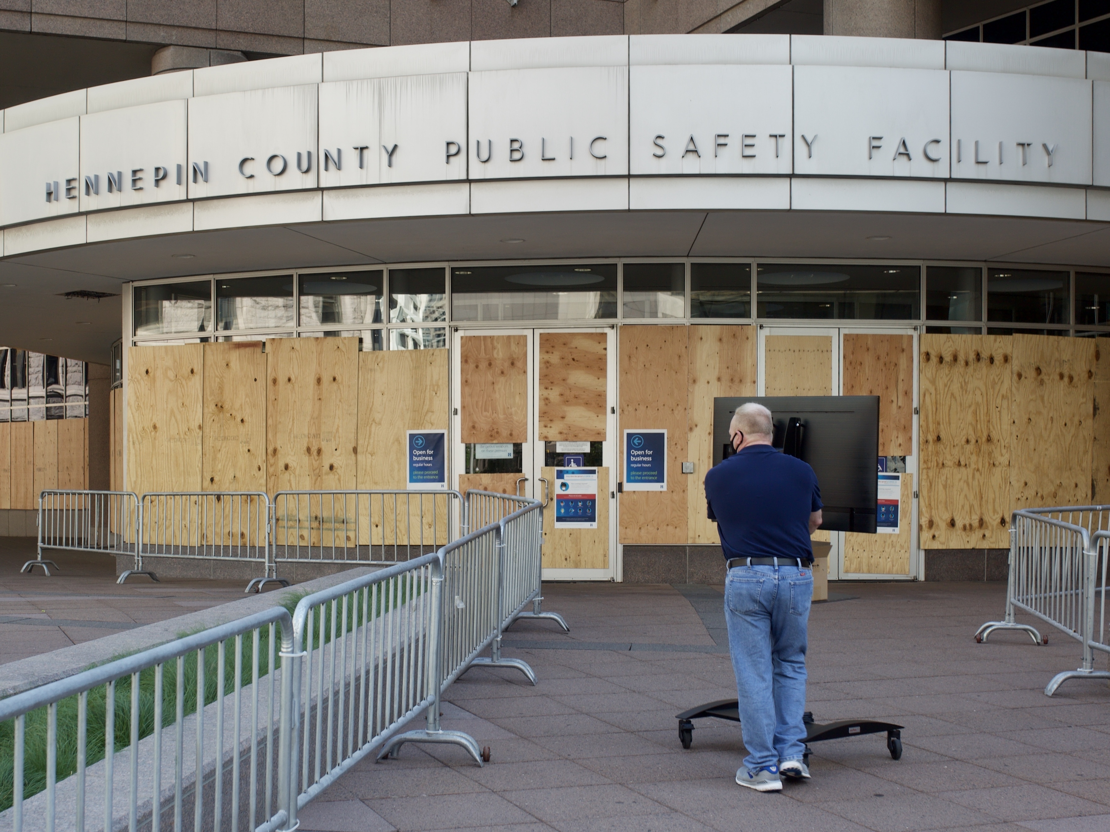 caption: A facility worker brings a TV inside the Hennepin County Public Safety Facility on Monday in Minneapolis, part of preparations for the first court hearing for former police Officer Derek Chauvin.