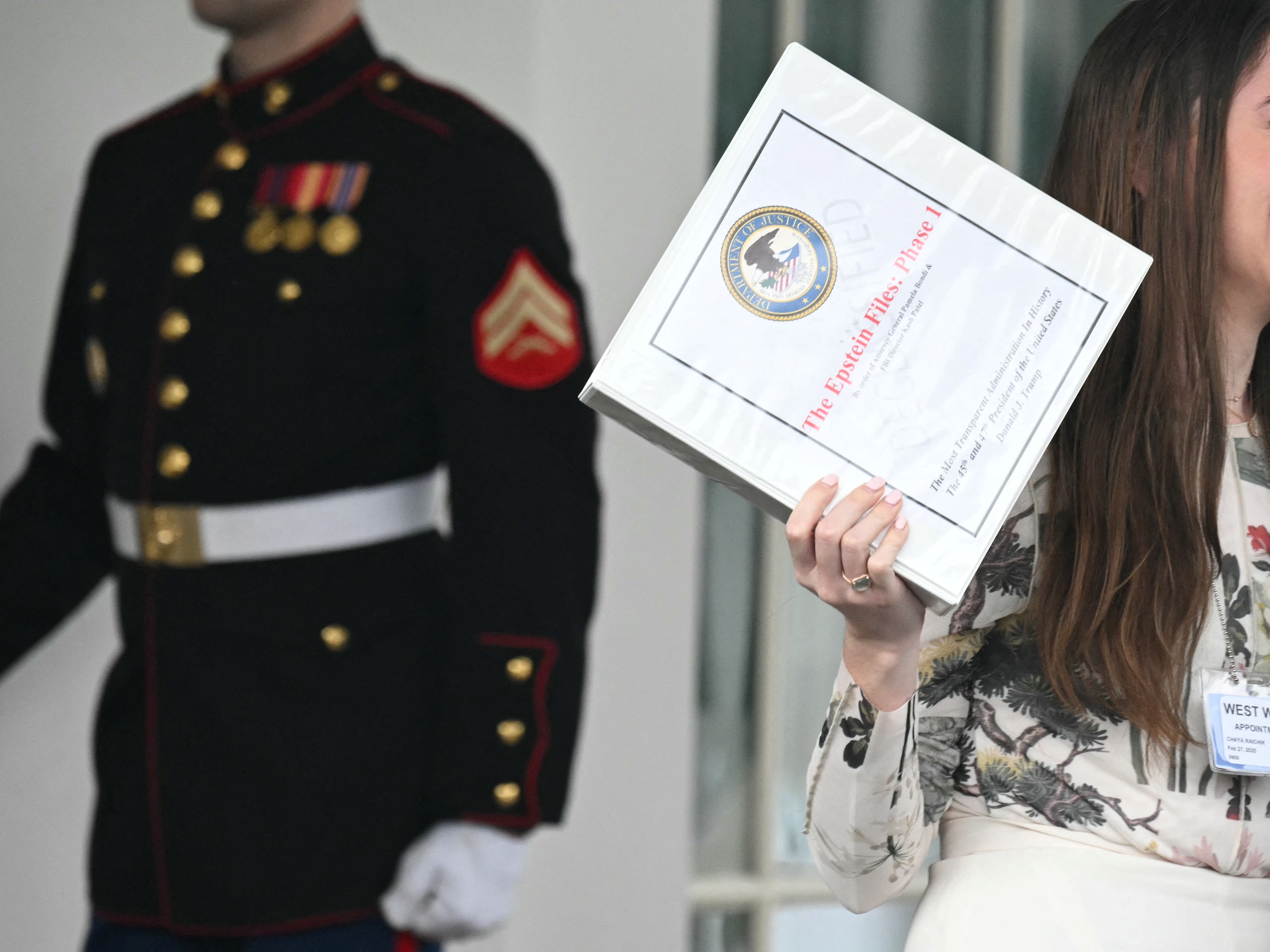 caption: Unidentified people carrying binders bearing the seal of the US Justice Department reading "The Epstein Files: Phase 1" walk out of the West Wing of the White House in February. The Trump administration had promised it would release documents on late tycoon and convicted sex trafficker Jeffrey Epstein who was found dead in his prison cell in 2019.