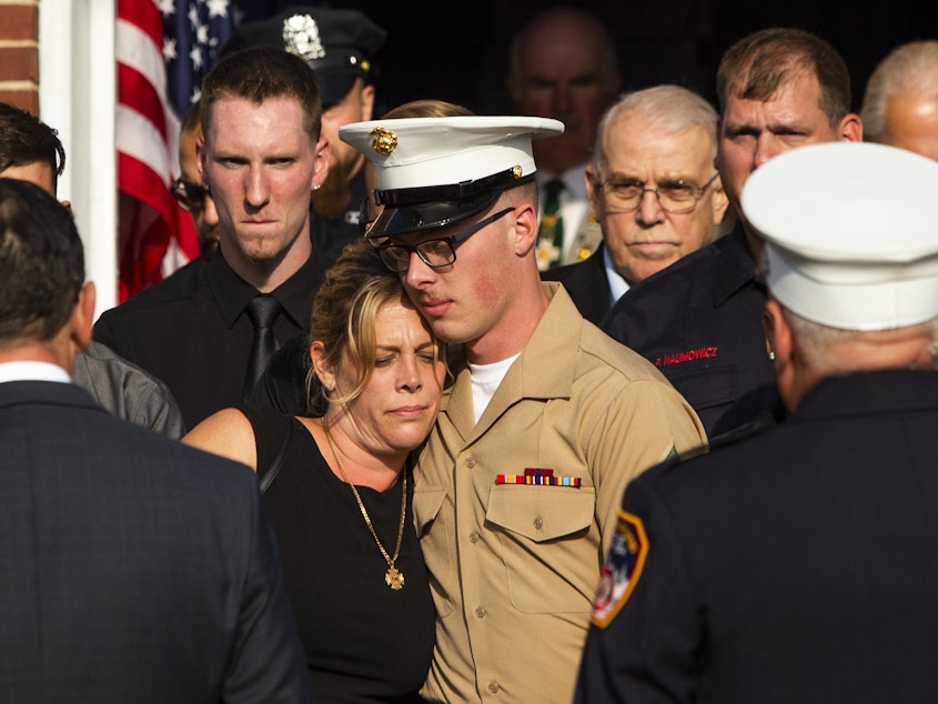 caption: Erika Starke, left, is comforted by her son, Michael Haub, as they attend a second funeral service for New York Fire Department firefighter Michael Haub, in Franklin Square, N.Y. The New York City medical examiner identified more of his remains recovered at ground zero.