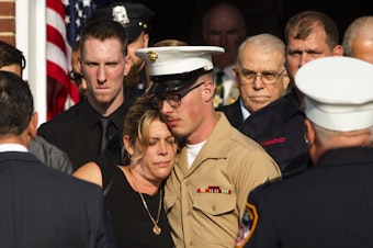 caption: Erika Starke, left, is comforted by her son, Michael Haub, as they attend a second funeral service for New York Fire Department firefighter Michael Haub, in Franklin Square, N.Y. The New York City medical examiner identified more of his remains recovered at ground zero.