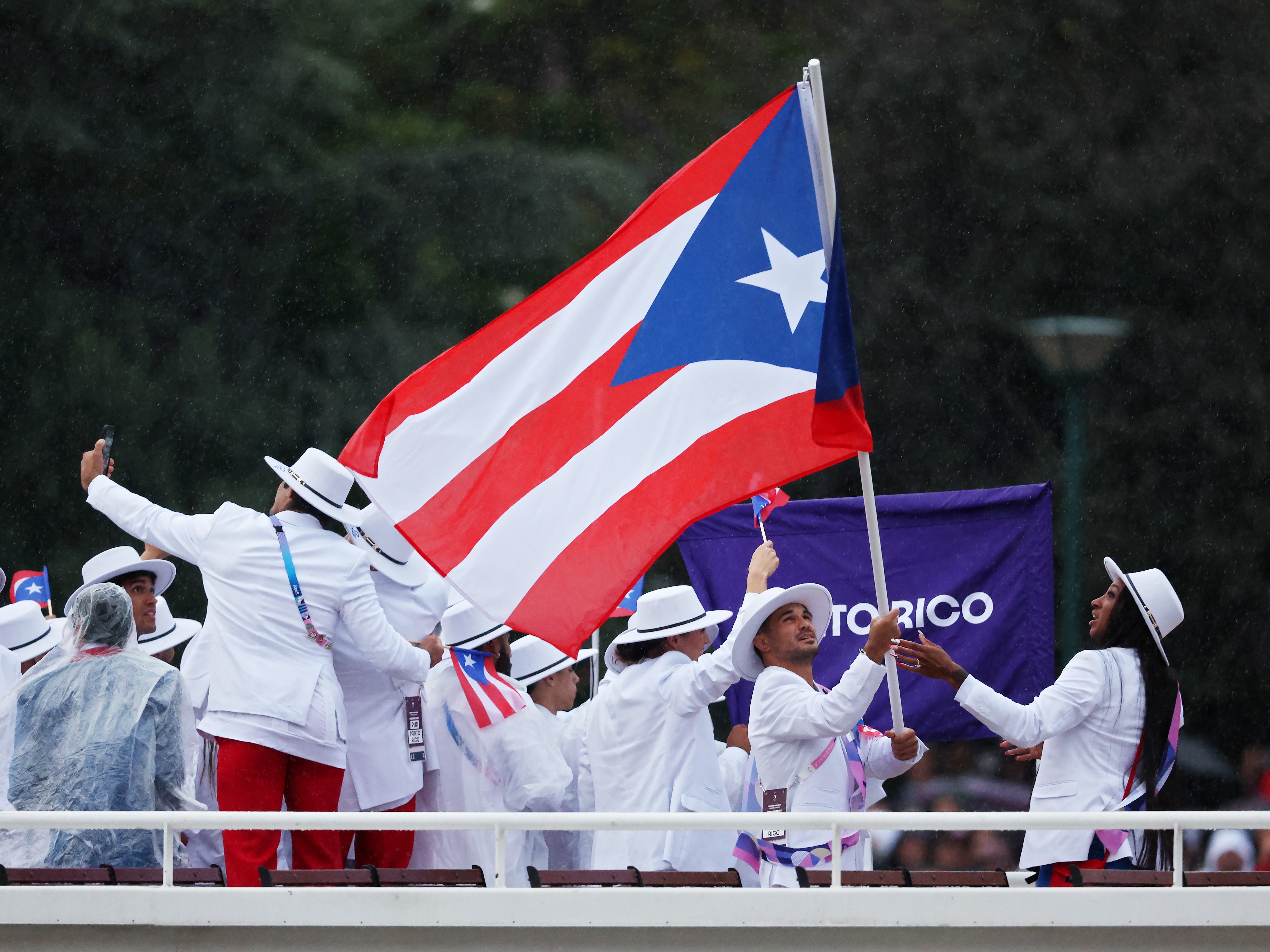 caption: Athletes of Team Puerto Rico are seen on a boat on the River Seine during the opening ceremony of the Olympic Games in Paris on July 26.