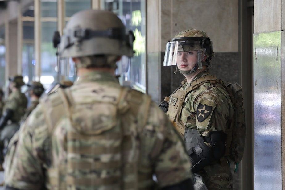 caption: A Washington National Guard soldier looks across at another as they stand guard outside a previously closed Macy's department store as a protest begins nearby Monday, June 1, 2020, in Seattle, following protests over the weekend over the death of George Floyd, a black man who was in police custody in Minneapolis. 