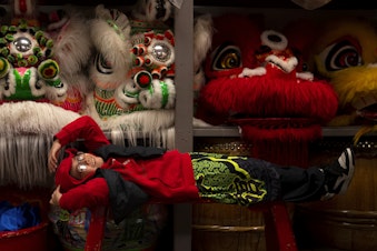 caption: Kyle Nguyen, 7, rests on a bench as the Mak Fai Dragon and Lion dancers get ready for several performances ahead of the Lunar New Year celebration on Saturday, Feb. 4, 2023, in Seattle’s Chinatown-International District. 