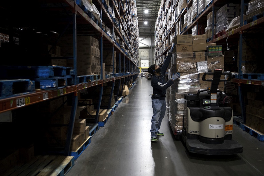 caption: Essential worker Monty Johnson, an order selector at Safeway's Distribution Center, works to gather items in an order on Monday, March 22, 2021, at the distribution center in Auburn. 