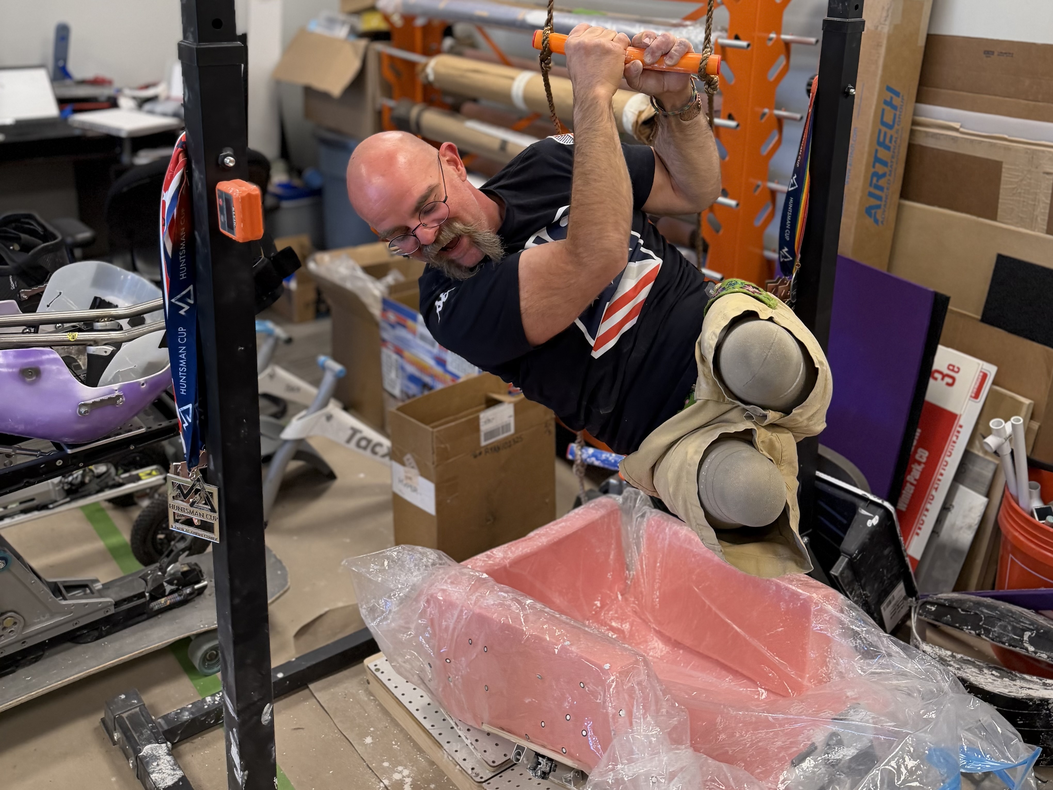 caption: Zach Williams, a U.S. para alpine skier, lowers himself into his molding rig. Williams was already a licensed prosthetist when he was introduced to his sport: skiing in a seated position. A double amputee, he's walked on prosthetics since age two. Now his business helps other Paralympians get the right fit for their competitive gear.