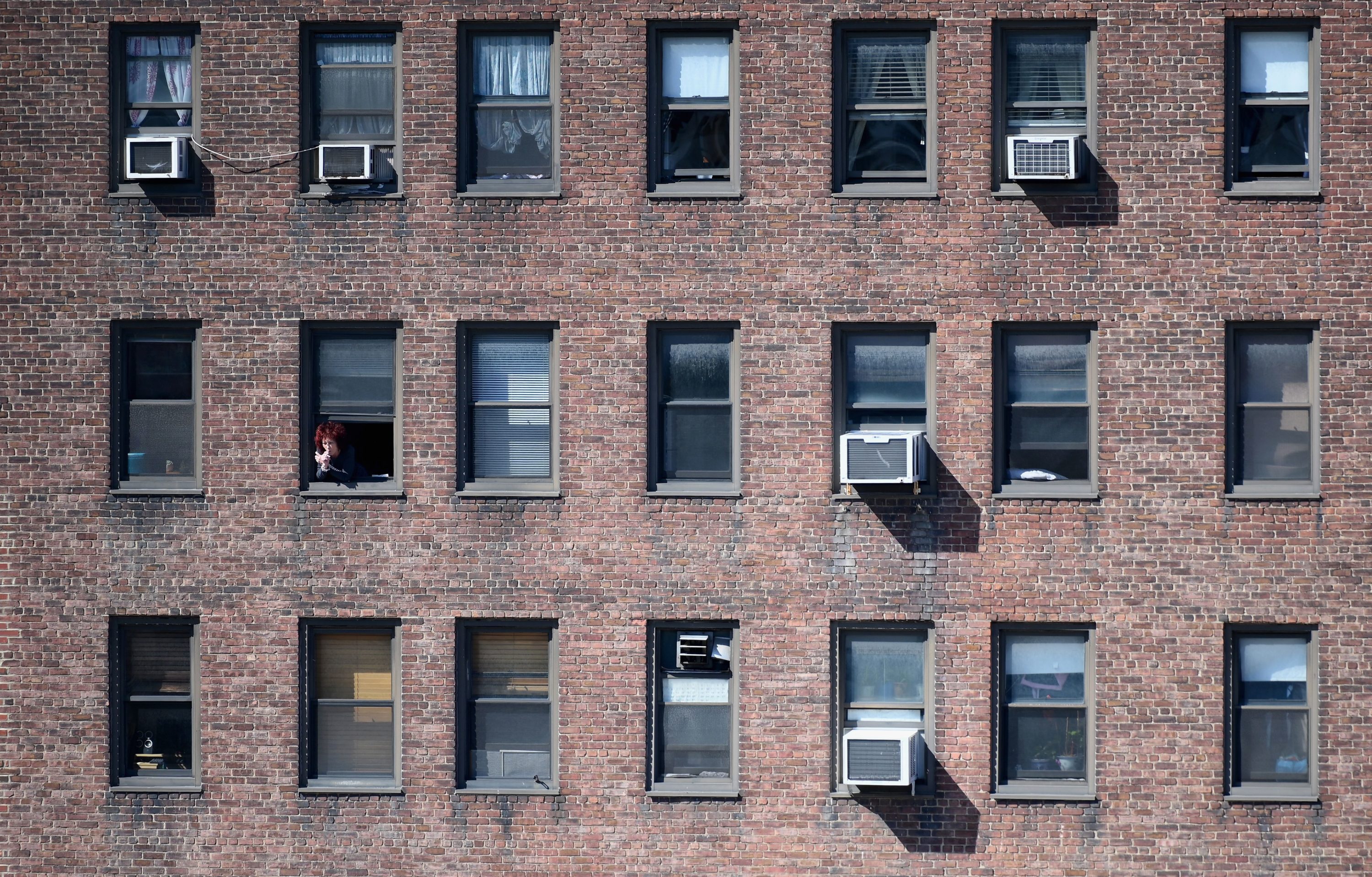 caption: A person looks at of their window on March 24, 2020 in New York City. U.S. lawmakers closed in on a deal Tuesday to help save the teetering economy by injecting nearly $2 trillion into pockets of struggling Americans, devastated businesses and hospitals struggling to contain the coronavirus pandemic. (ANGELA WEISS/AFP via Getty Images)