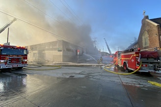 caption: Seattle fire crews respond to a two-alarm fire at a vacant warehouse in the 1000 block of South King Street on July 20, 2023. 