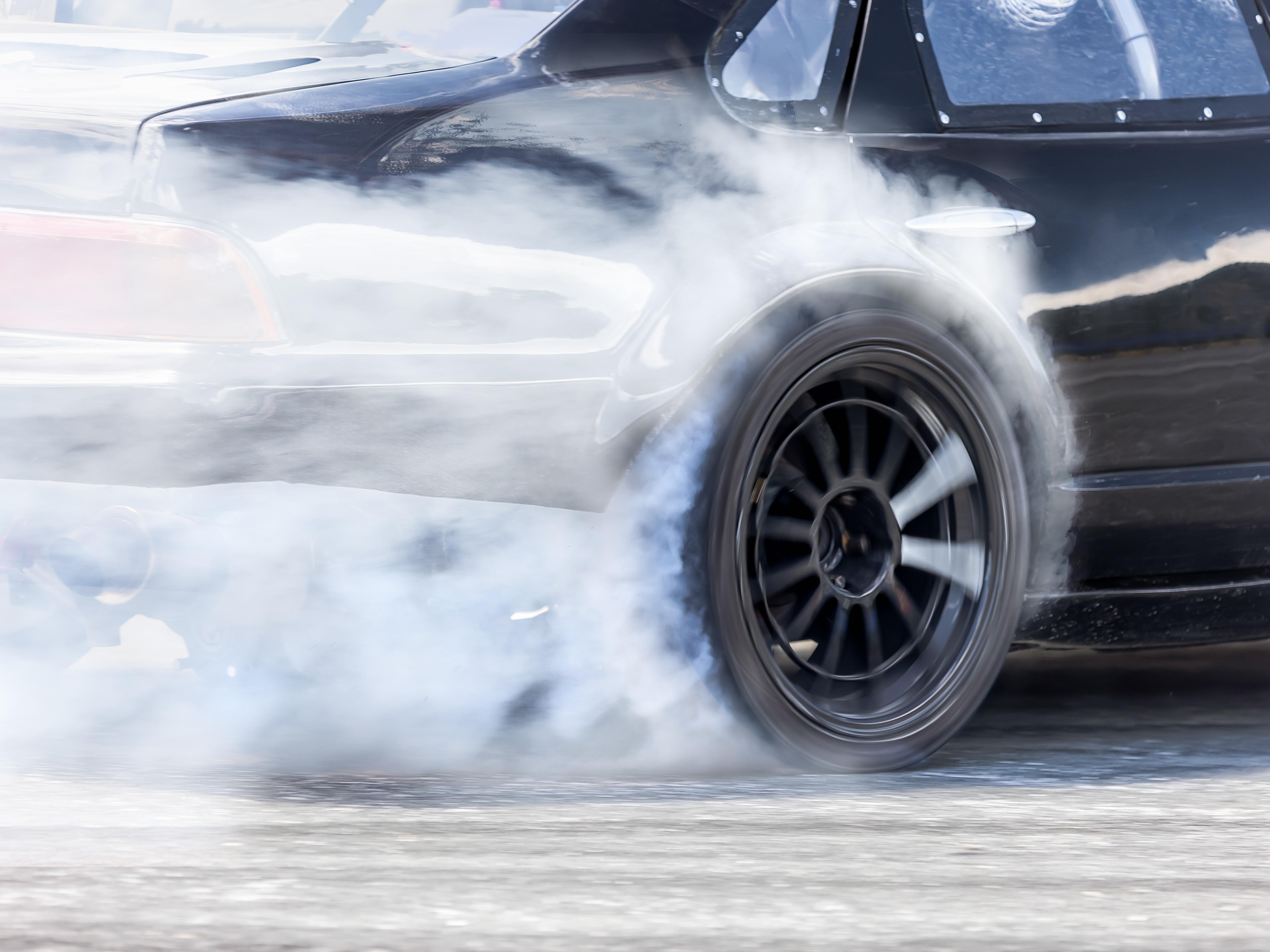 caption: Illustration: Burning rubber at a race. At illegal "sideshows," drivers show off their cars and skills by doing burn-outs and donuts, often shutting down public streets.