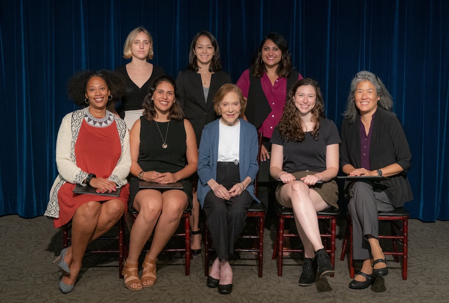 caption: The late Rosalynn Carter, center, poses with recipients of the 2018-2019 Rosalynn Carter Mental Health Journalism Fellowship. KUOW's Deborah Wang is at right.