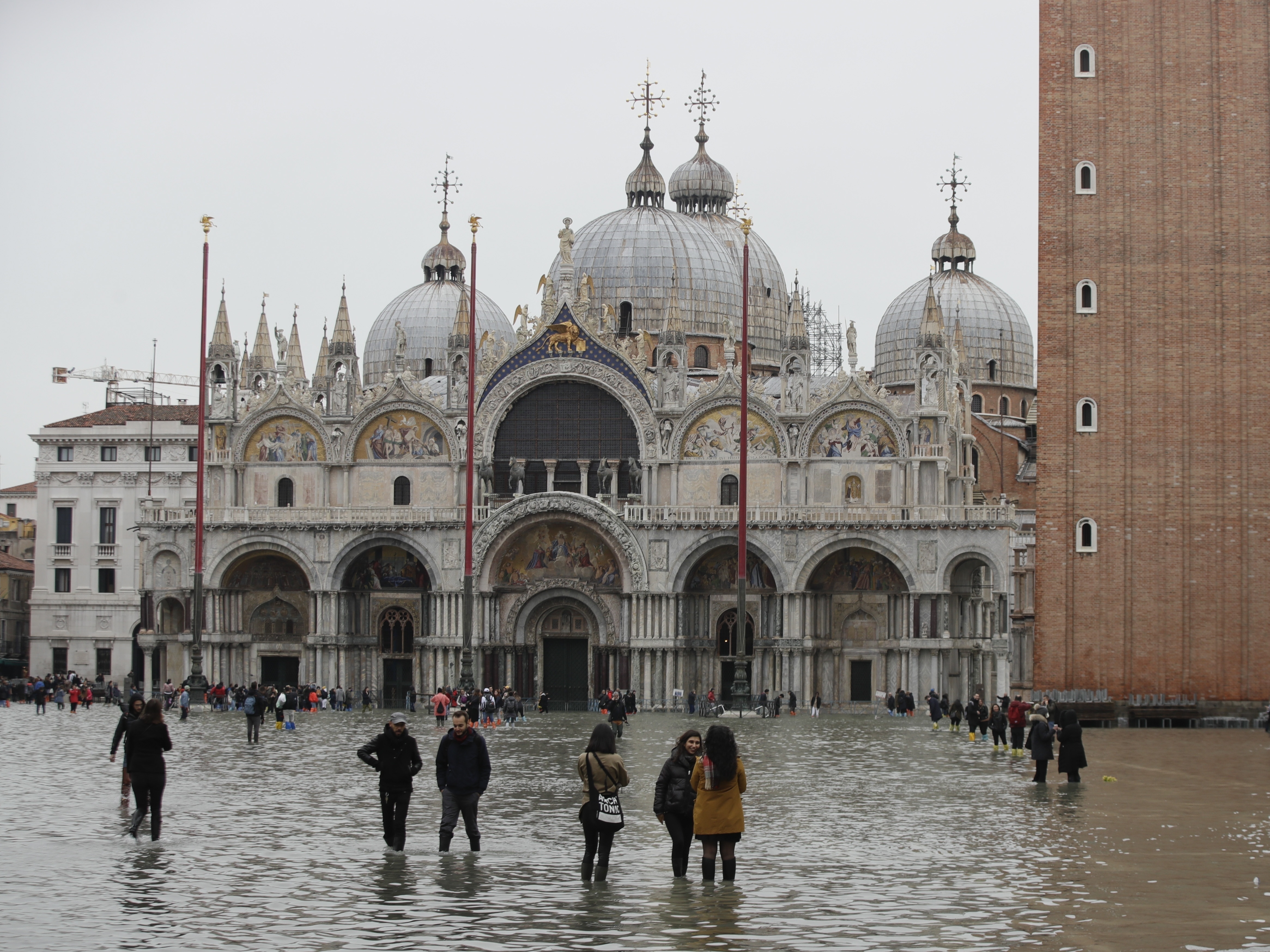 caption: People in front of St. Mark's Basilica wade in flood water in Venice on Wednesday.