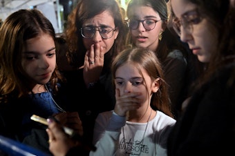 caption: A mother and her children react to the news that Hanna Katzir, who the Palestine Islamic Jihad claimed died in captivity, is among the 13 Israelis released. They are watching the news on their phone outside the Museum of Tel Aviv on Friday.