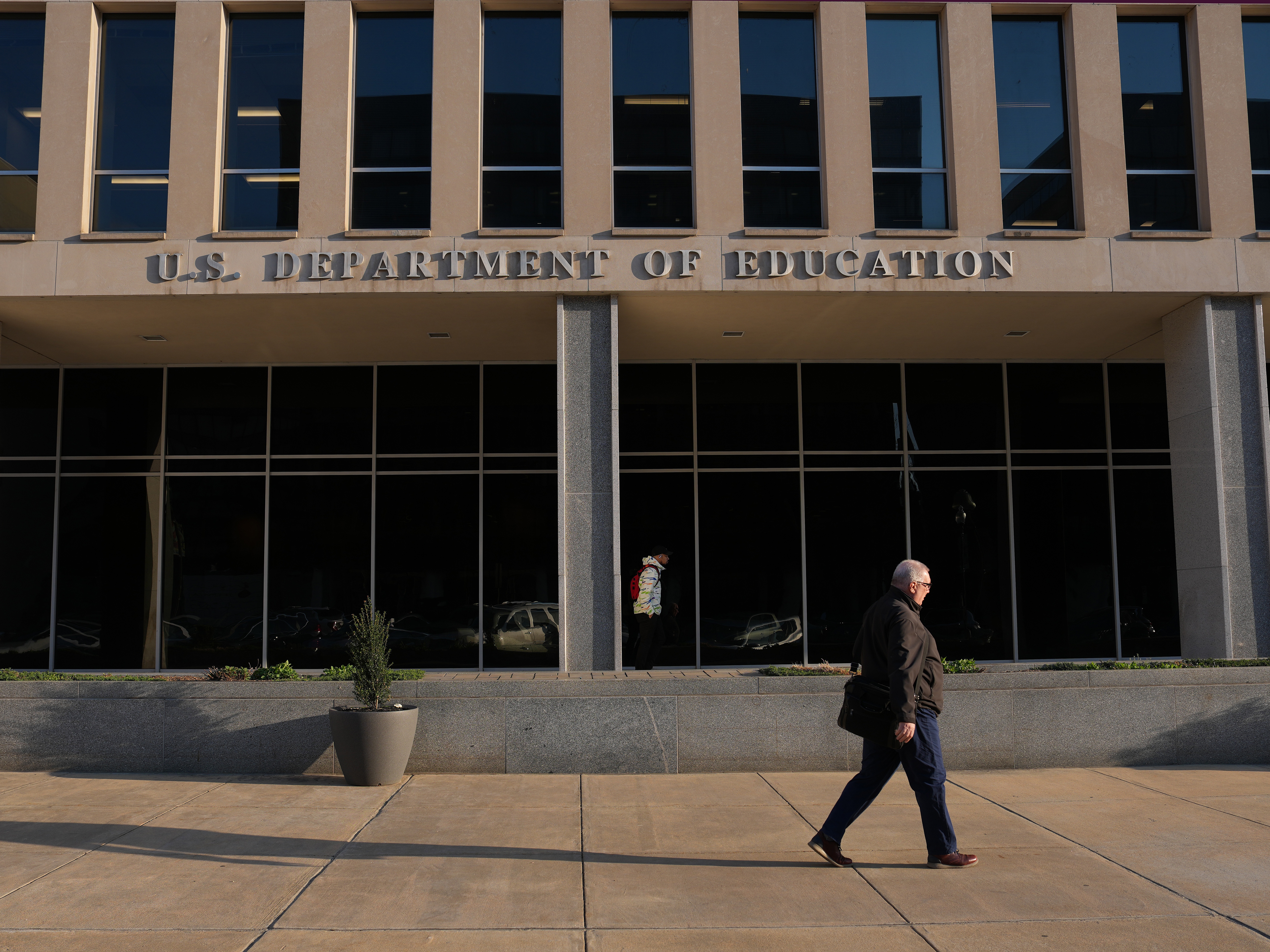 caption: A person walks past the U.S. Department of Education in Washington, D.C. A lawsuit from a federal workers union argues that changes to employees' out-of-office messages to include partisan language violate the First Amendment.