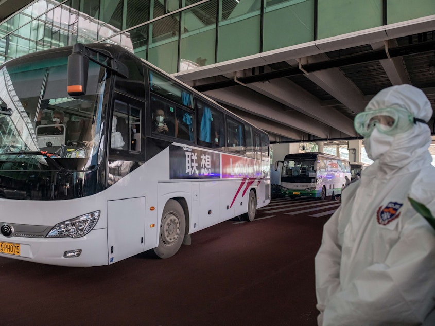 caption: A bus carrying members of the World Health Organization team investigating the origins of the COVID-19 pandemic leaves Wuhan's airport following their arrival at a cordoned-off section in the international arrivals area on Thursday.