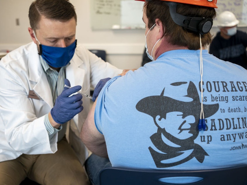caption: A pharmacist administers a dose of the COVID-19 vaccine to a worker at a processing plant in Arkansas City, Kan., on Friday, March 5, 2021. Researchers are concerned that vaccination rates in some rural communities may not keep up with urban rates.
