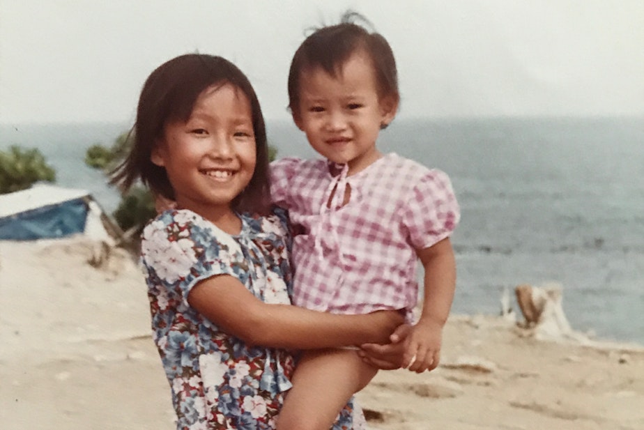 caption: Eight-year-old Diem Pham holds her 1-year-old cousin Kim Pham at a refugee camp in Malaysia in May 1980.