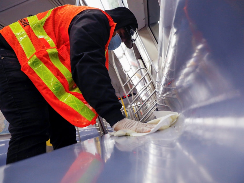 caption: A worker wipes down surfaces on a New York City subway car to disinfect seats during the coronavirus outbreak. The CDC is clarifying its guidance on touching surfaces after a change to its website triggered news reports.