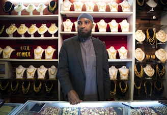 caption: Ali Jama stands behind the counter of Haveniceday Jewelry on Thursday, April 19, 2018, in Tukwila. 