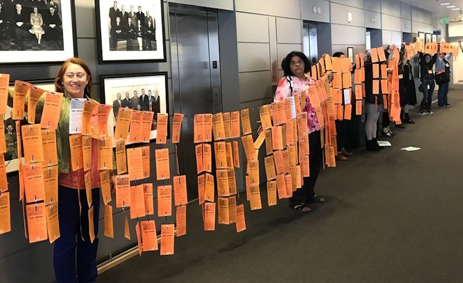 caption: Seattle Silence Breakers unveiled postcards and banners Thursday, May 31 2018, that read 'Mayor Durkan, Stop All harassment & Discrimination now!'