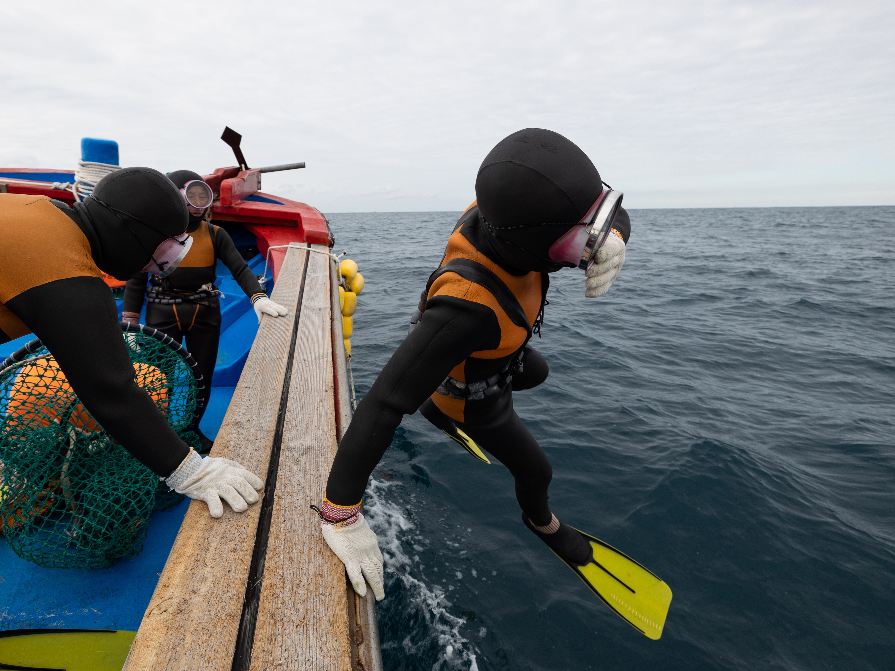 caption: A South Korean female free diver jumps into the sea from a boat off the coast of Jeju Island on Jan. 15, 2022. New research has found that these women, known as Haenyeo, have specific genetic adaptations connected to cold tolerance and blood pressure.
