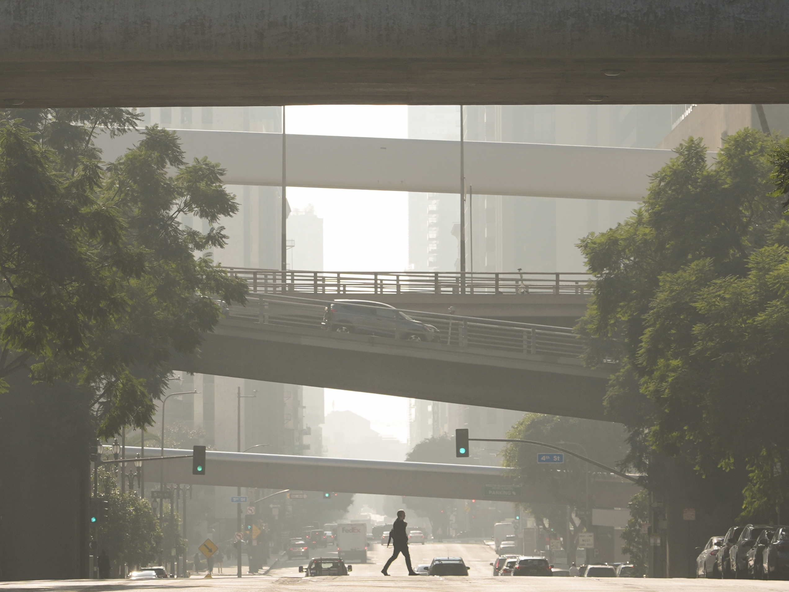 caption: A person crosses a street as smog fills the air Wednesday, Dec. 4, 2024, in Los Angeles.