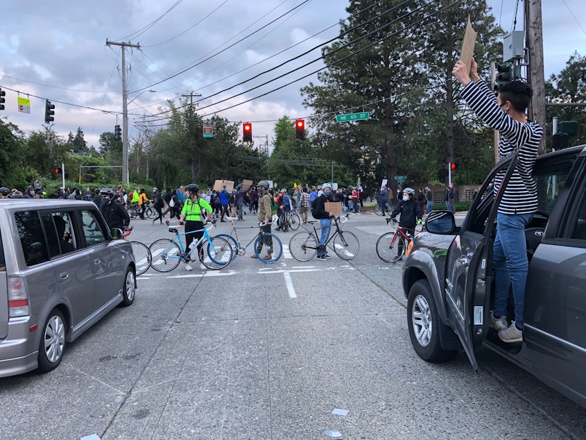 caption: Bicyclists block an intersection as people march between Magnuson Park and University Village in Seattle on Saturday, June 6.