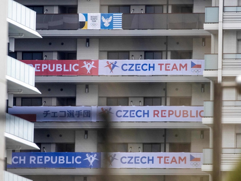 caption: Banners of the Czech Republic (bottom) and the Olympic Refugee teams (top) are seen on a building at the Olympic and Paralympic Village ahead of the 2020 Tokyo Olympics. The Czech team is investigating a cluster of coronavirus cases.