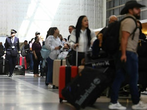 caption: Travelers and their luggage in a terminal at Los Angeles International Airport in August 2023.