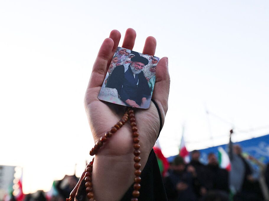 caption: A person holds a picture of Iran's supreme leader Ayatollah Ali Khamenei, who was killed in joint US and Israeli strikes, as people mourn at a square in Tehran on March 1, 2026.