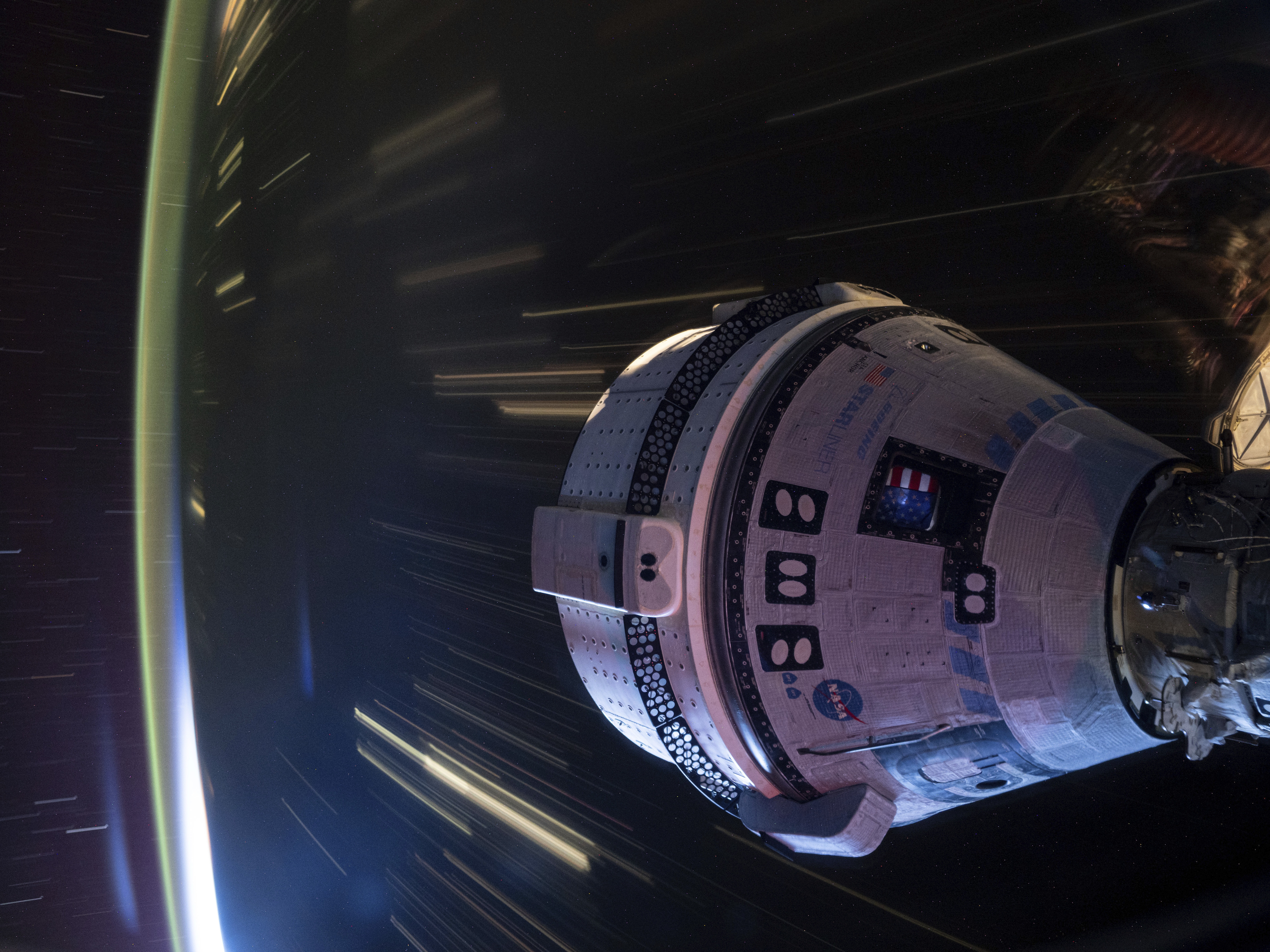 caption: In this long-exposure photo provided by NASA, Boeing's Starliner spacecraft is docked to the Harmony module of the International Space Station on July 3.