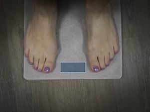 Ozempic. Weight loss. Close up to female bare feet with pedicure standing on scales with empty display. Woman standing on bathroom scale to check her weight. Weighting. Wellnes and health