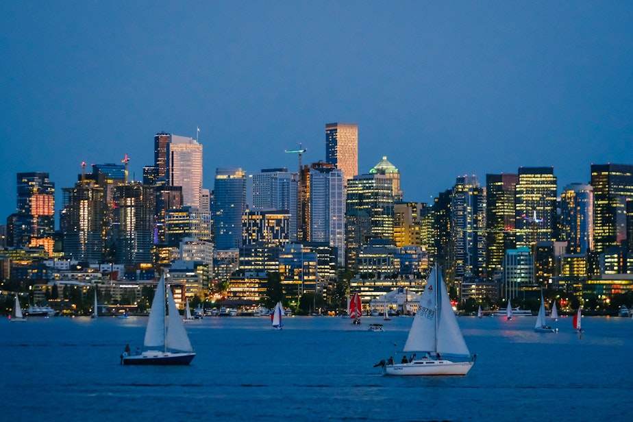 caption: Boats circle Lake Union at dusk during the final Duck Dodge sailing race of the season, September 7, 2021. Sailors have been gathering Tuesday summer nights at the lake to participate in the recreational regatta for the past 48 years.