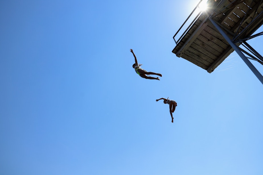 caption: Two people are jumping out of a platform in the Laurelhurst Beach Club June 28, 2021.