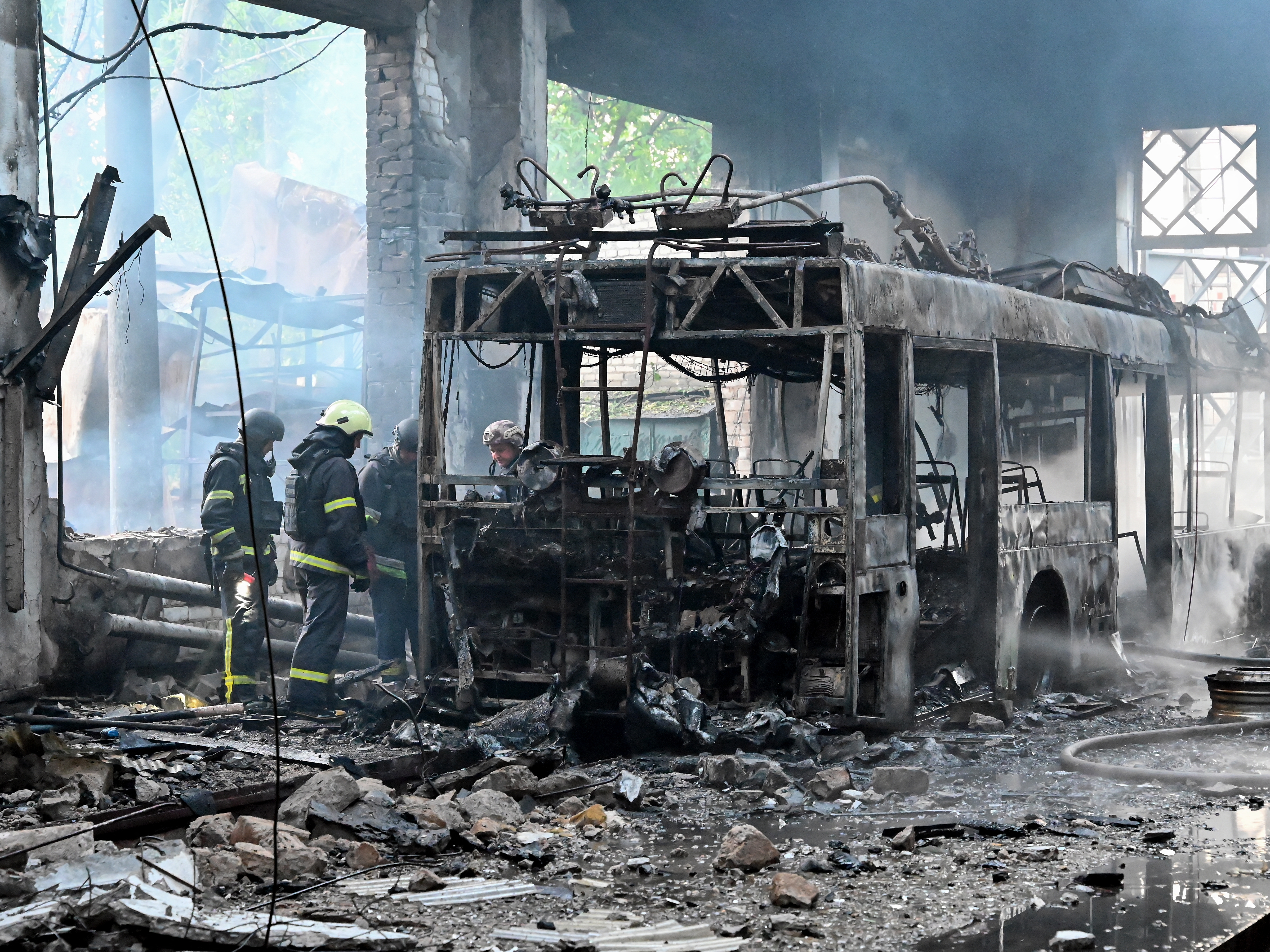 caption: Ukrainian rescuers work to extinguish a fire in a trolleybus depot following a drone strike in Kharkiv on Friday, amid the Russian invasion of Ukraine.