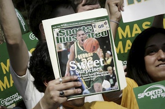 caption: A George Mason University fan holds up the cover of Sports Illustrated magazine at a send-off for the team, on March 29, 2006, in Fairfax, Va. The union representing the magazine's staff said that SI's publisher plans to cut "a significant number, possibly all" of its union-represented staff.