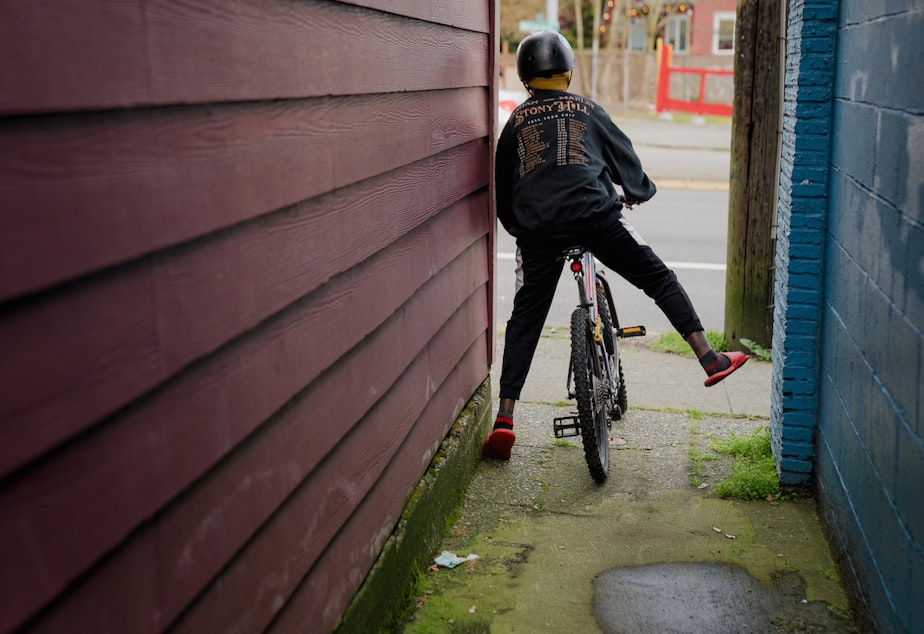 caption: Getahun bikes through an alley on Sunday, March 13, 2022, in Seattle, Washington.