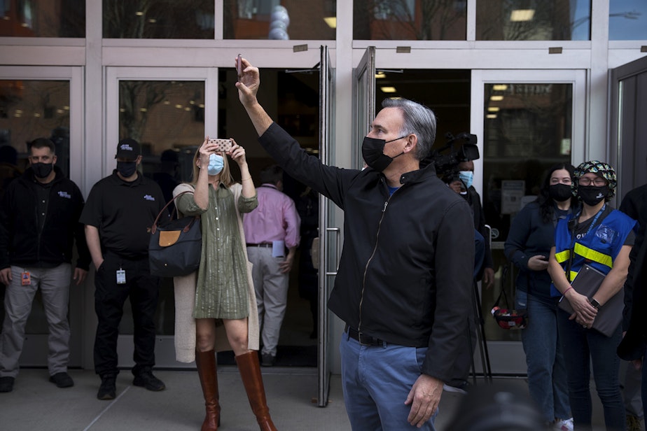 caption: King County Executive Dow Constantine takes a picture of the line of people arriving to be vaccinated against Covid-19 at the new civilian-led mass vaccination site at Lumen Field Event Center on Saturday, March 13, 2021, in Seattle.