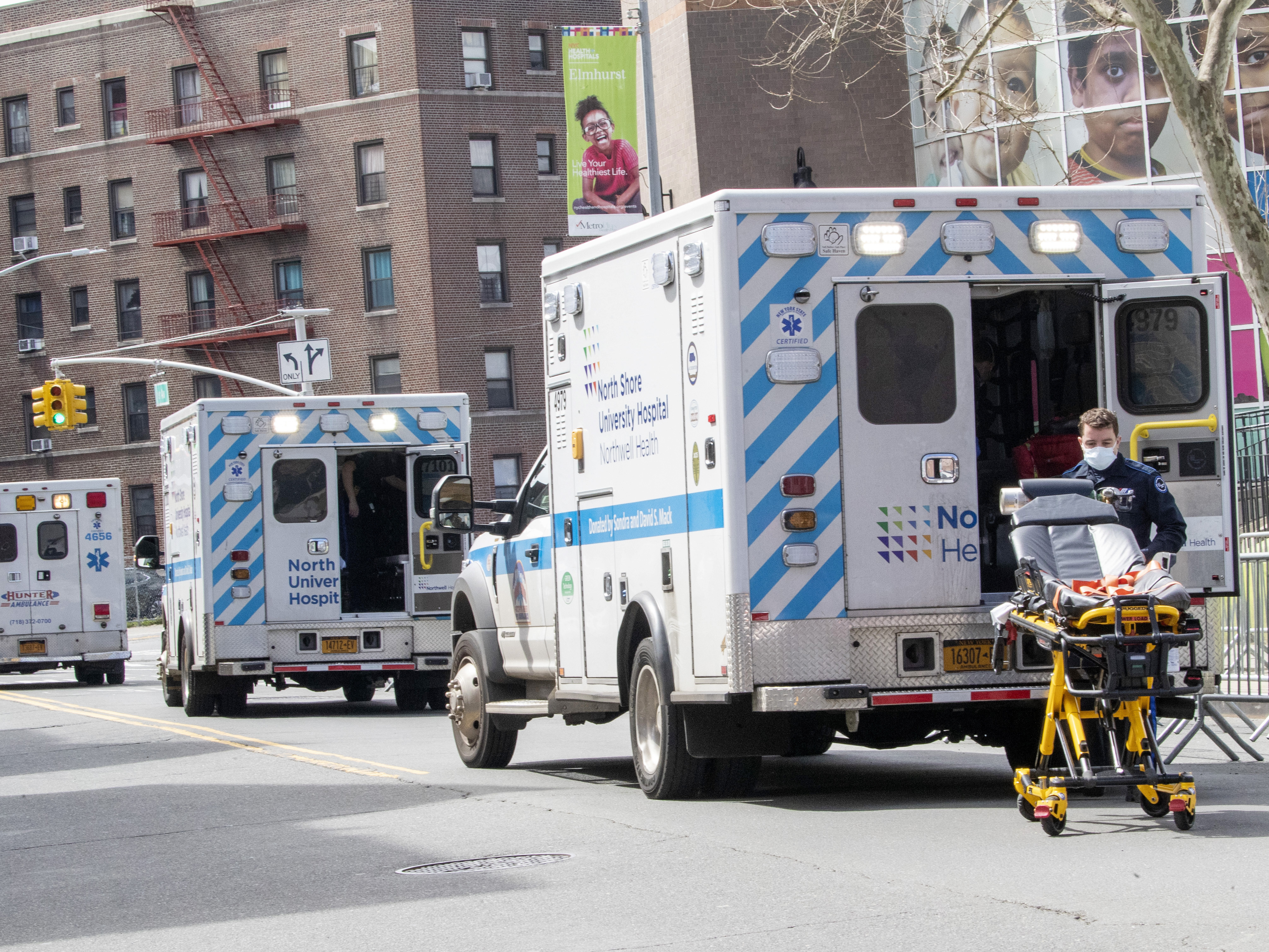 caption: Ambulances line the street outside Elmhurst Hospital Center on Saturday in the Queens borough of New York.