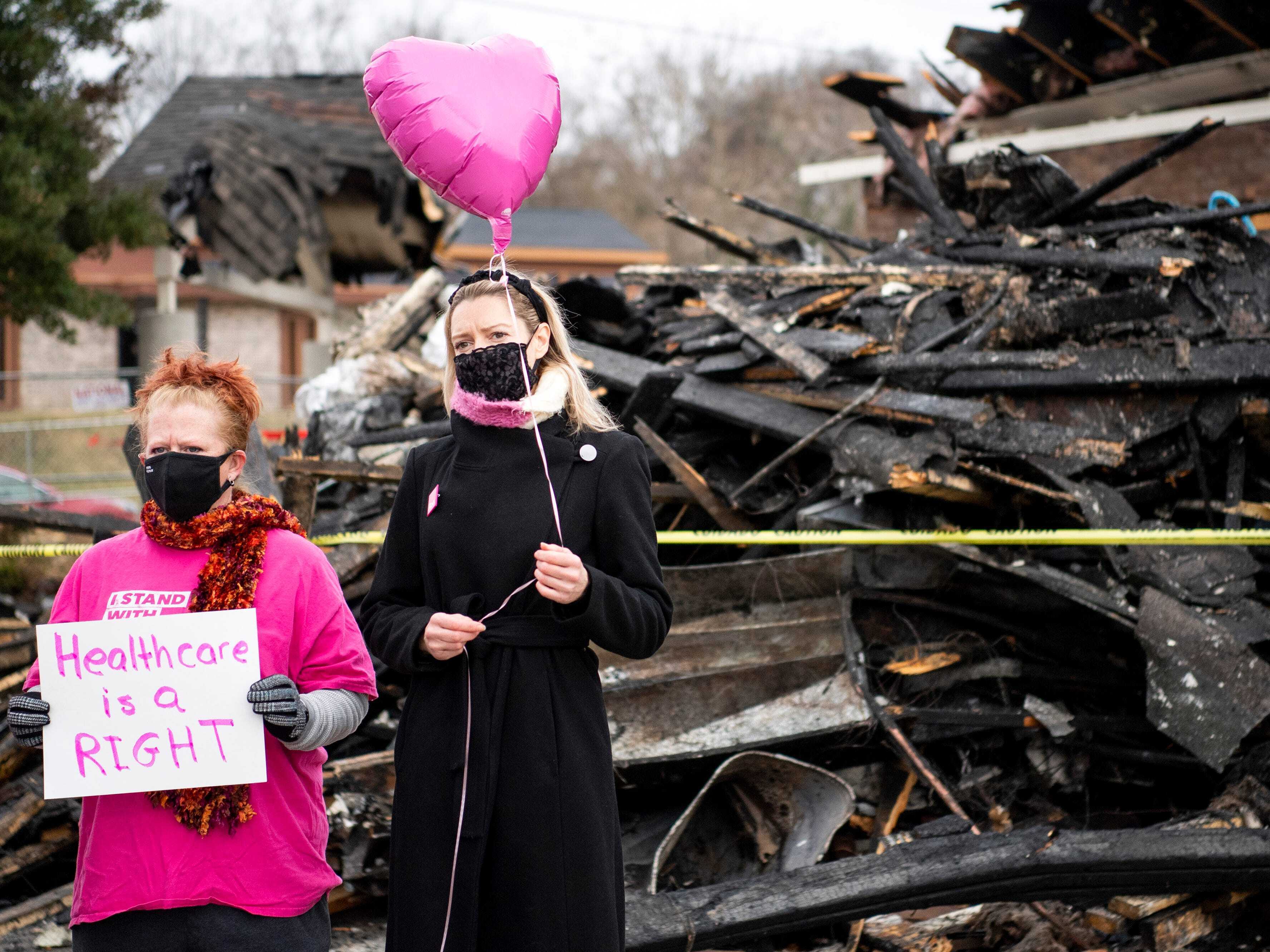 caption: Supporters stand in front of a pile of fire burned wreckage at Knoxville's Planned Parenthood on Jan. 6.