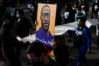 caption: Demonstrators carry a scroll listing the names of people killed by police during a march in honor of George Floyd on March 7, 2021 in Minneapolis, Minnesota.