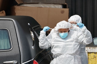 caption: Funeral home workers put on protective gear to retrieve a body from a refrigerated truck outside of a Brooklyn hospital in early April. As of Sunday, the U.S. reported the most coronavirus deaths in the world, surpassing Italy.