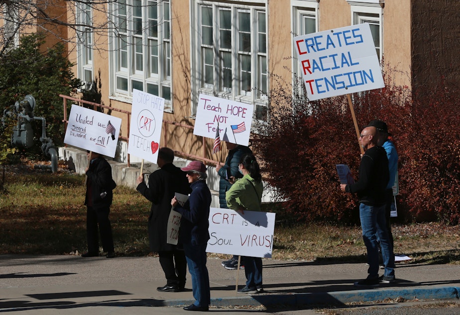 caption: People protest outside the offices of the New Mexico Public Education Department's office, on Nov. 12, 2021, in Albuquerque, N.M. As conservative-run states across the U.S. move to restrict discussion of race, gender, and identity in the classroom, progressive-run states are trying to prioritize those discussions.