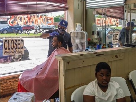 caption: Marian Searcy cuts Shaquille Sanders' hair at Edward's Barber Shop in Macon, Ga. on Friday, the first day Gov. Brian Kemp said some businesses could reopen.