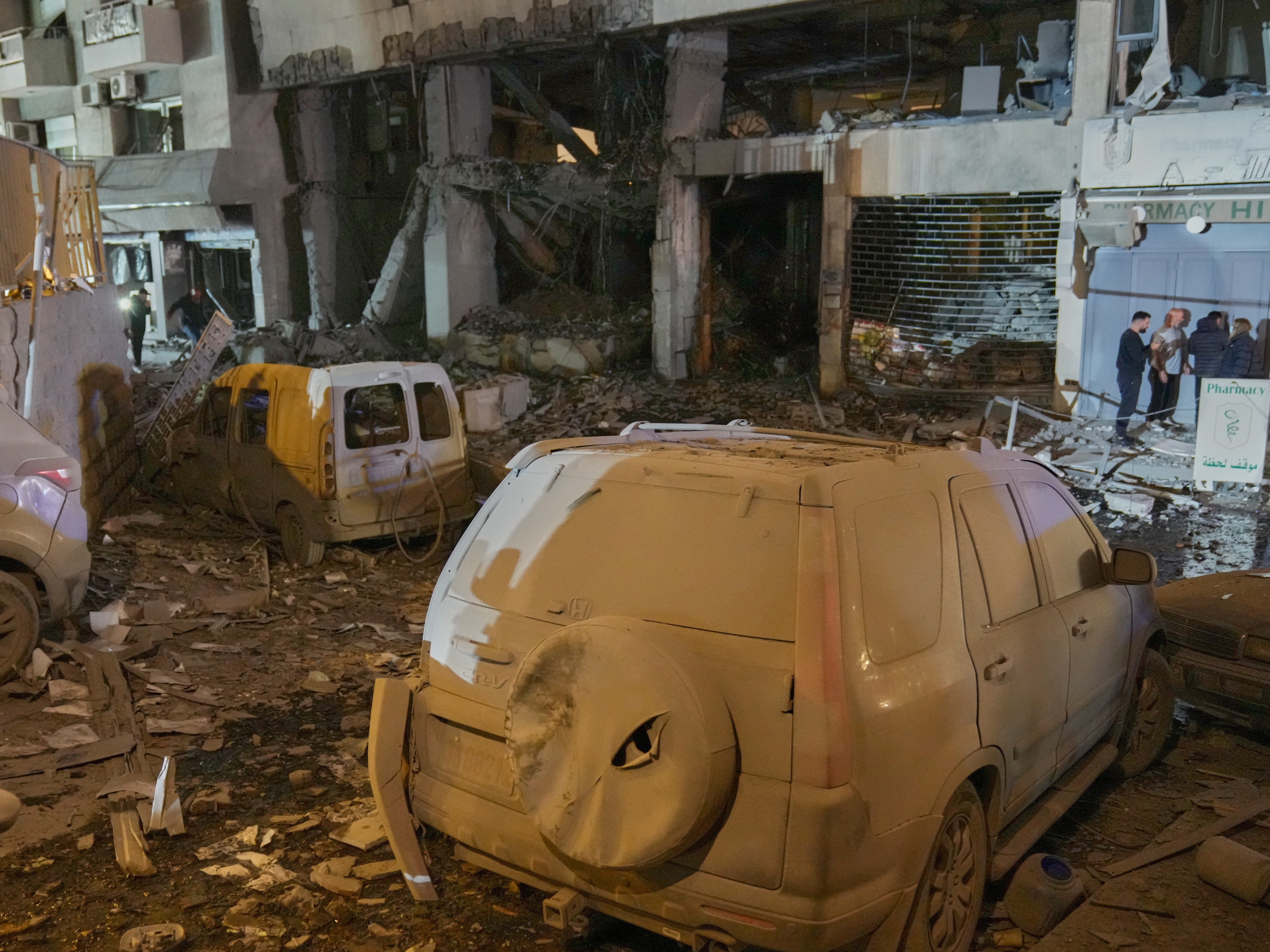 caption: People inspect the site of a destroyed branch of Al-Qard Al-Hassan, a non-bank financial institution run by Hezbollah, which was hit by an Israeli airstrike in central Beirut on Thursday.