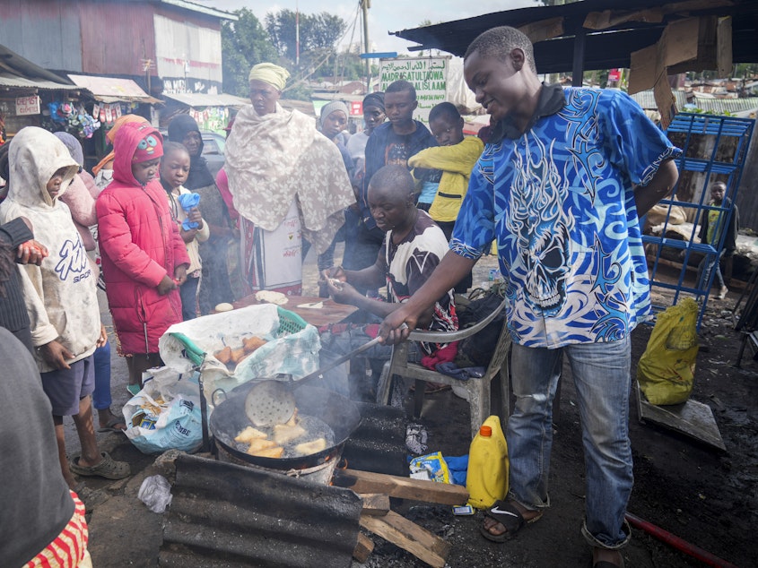 caption: A man uses cooking oil to fry Mandazi, a type of fried bread, on a street in the low-income Kibera neighborhood of Nairobi, Kenya, Wednesday, April 20, 2022.