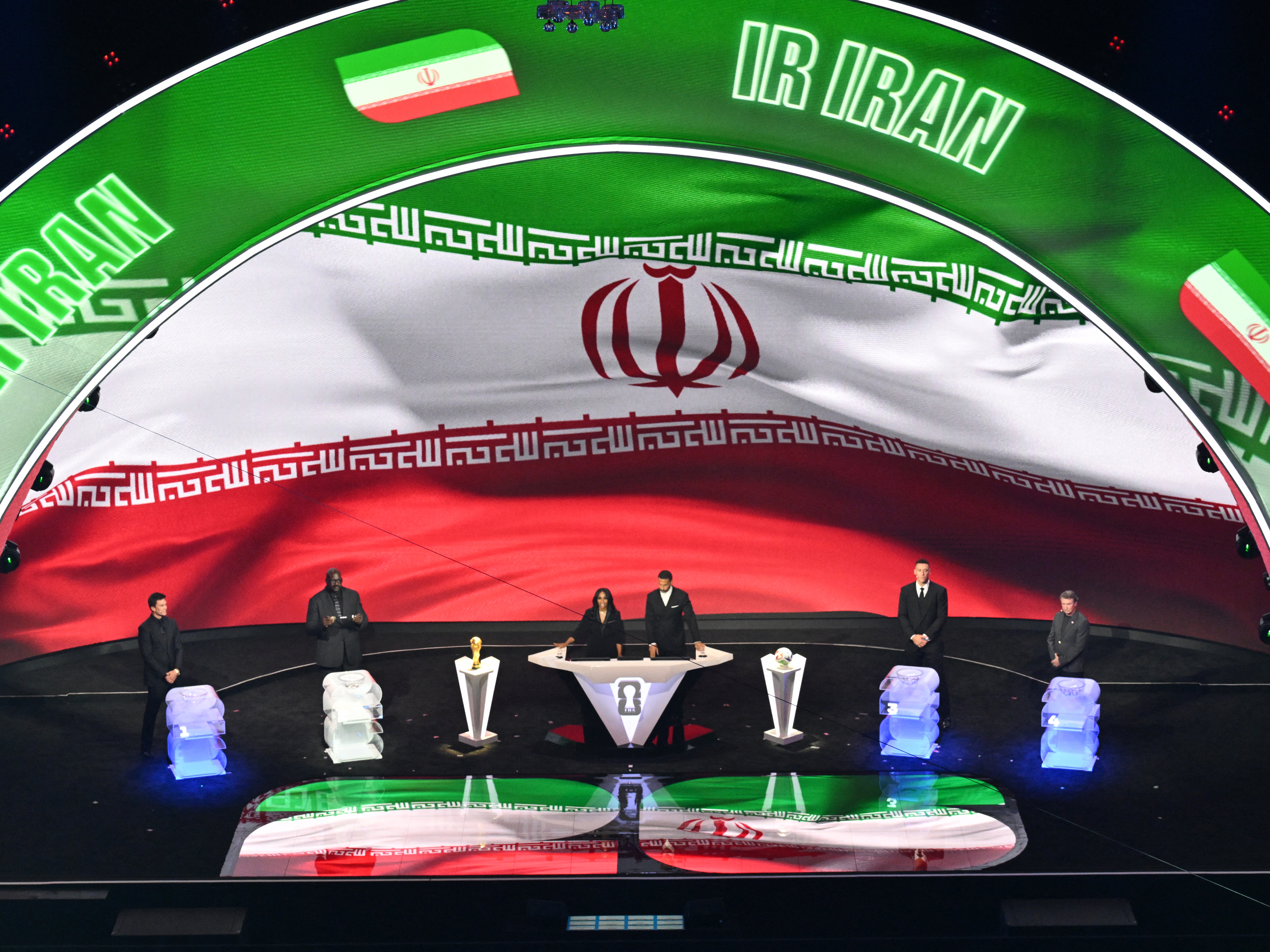 caption: Iran's flag is displayed on a screen during the draw for the 2026 FIFA Football World Cup taking place in the U.S., Canada and Mexico, at the Kennedy Center, in Washington, D.C., on December 5, 2025. Iran's sports minister says the team now won't play in this summer's tournament because of the U.S. attacks on Iran.