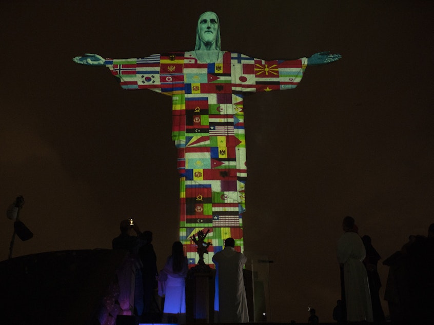 caption: The Christ the Redeemer statue in Rio de Janeiro, Brazil, was lit up with the flags of countries currently afflicted by the coronavirus.
