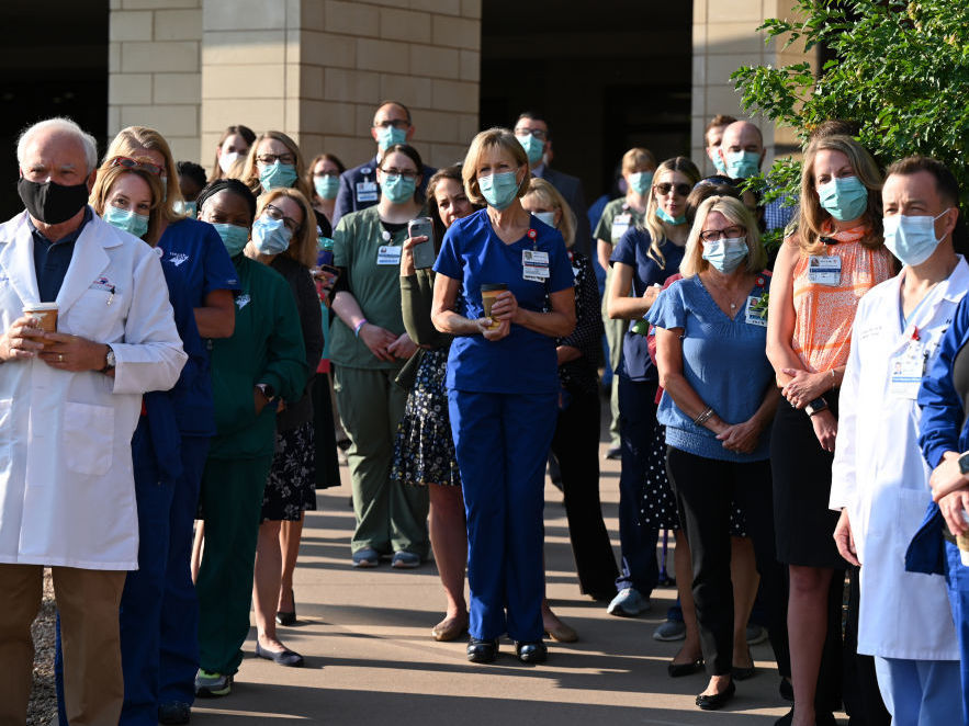 caption: Frontline workers at a medical center in Aurora, Colo., gather for a COVID-19 memorial on Thursday, July 15, to commemorate the lives lost to the pandemic. New estimates say many thousands more will die in the U.S. this summer and fall.