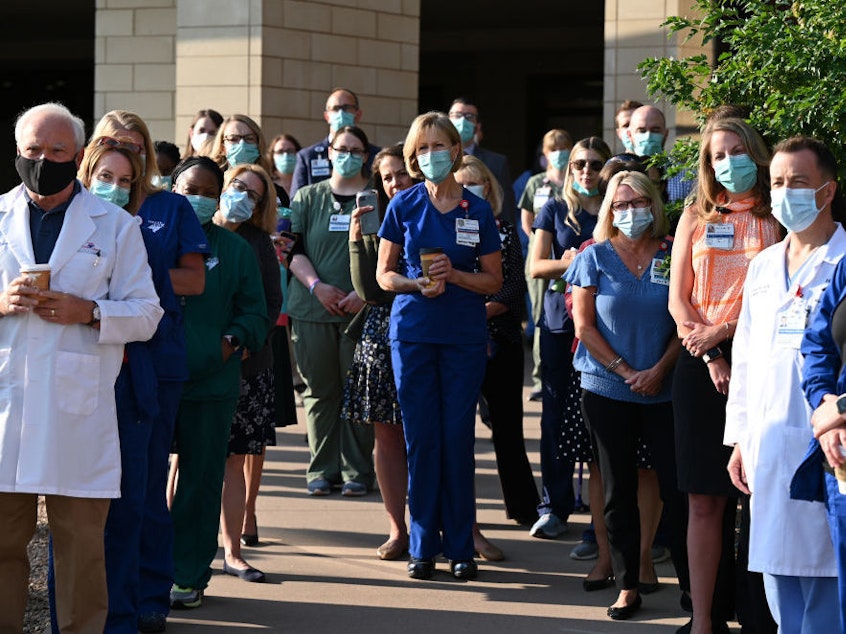 caption: Frontline workers at a medical center in Aurora, Colo., gather for a COVID-19 memorial on Thursday, July 15, to commemorate the lives lost to the pandemic. New estimates say many thousands more will die in the U.S. this summer and fall.